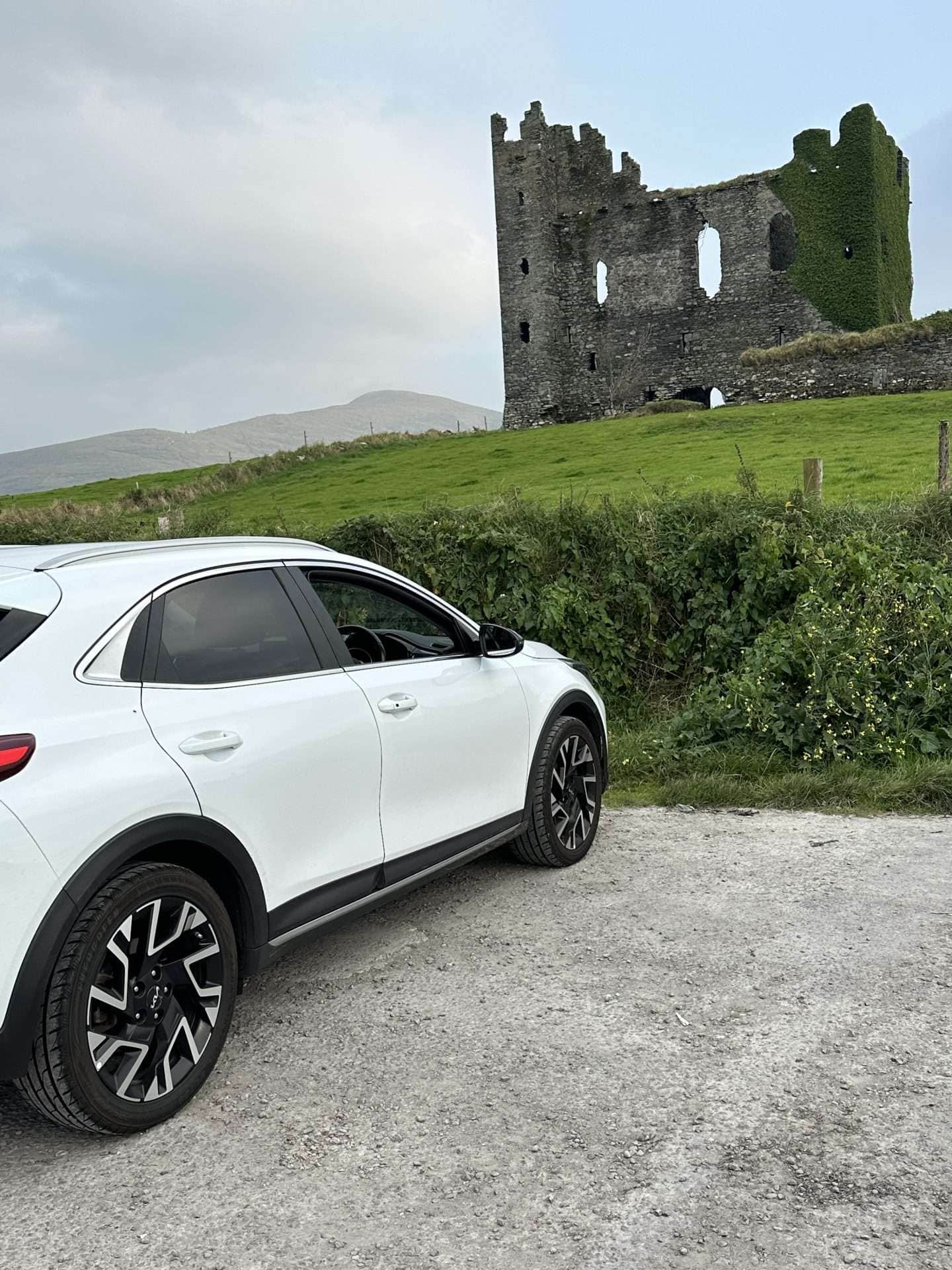 car parked by abandoned castle - driving in ireland