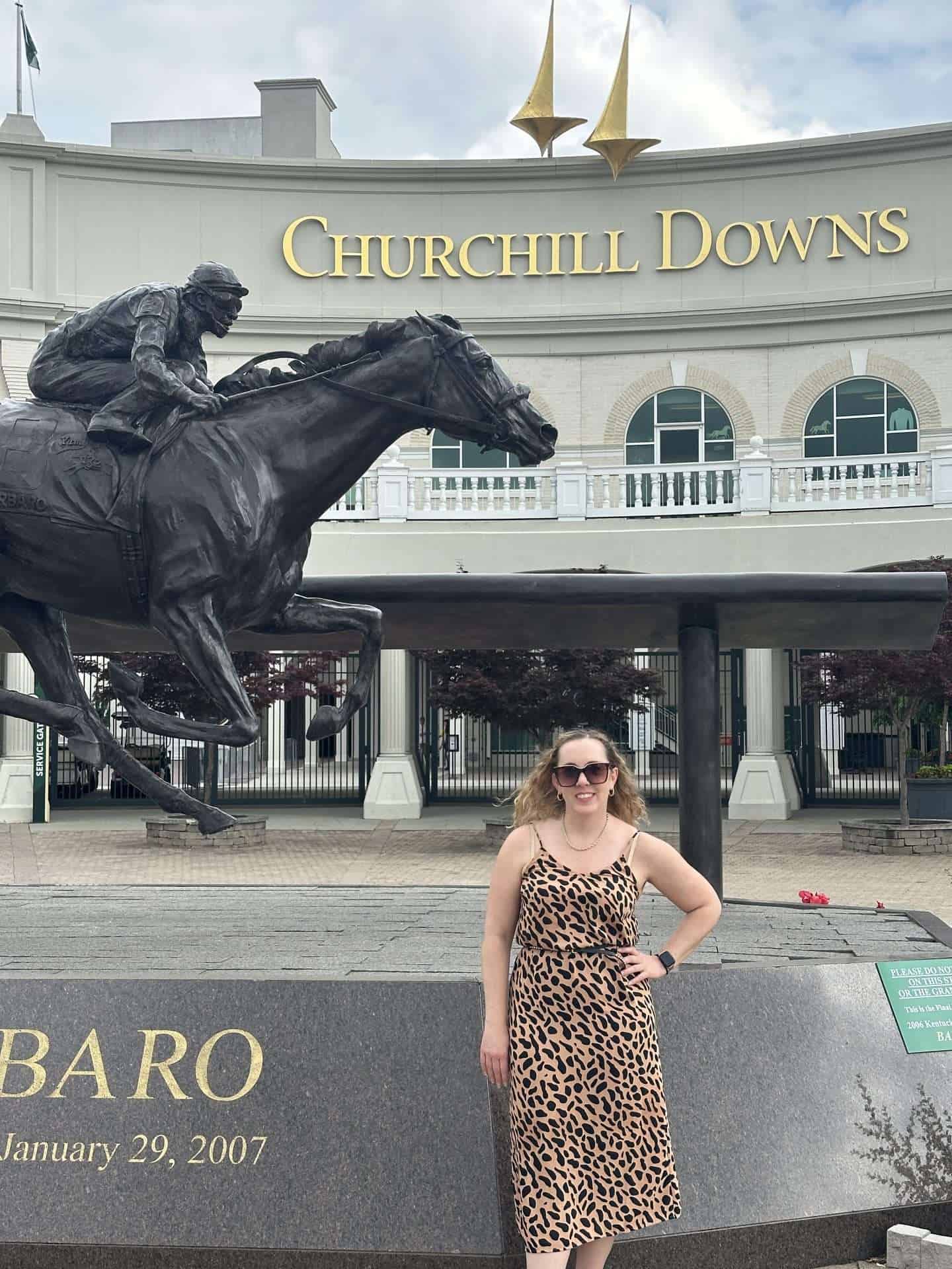 carli standing outside churchill downs next to horse statue