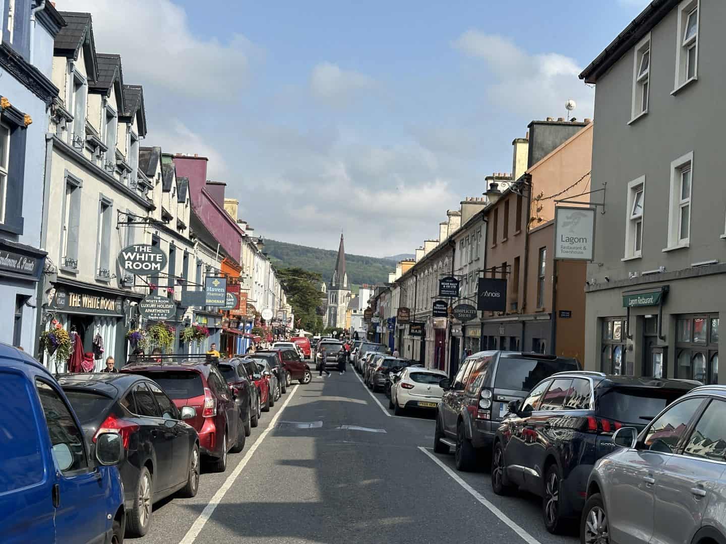 view of main street in kenmare with colorful shops and curch in the distance