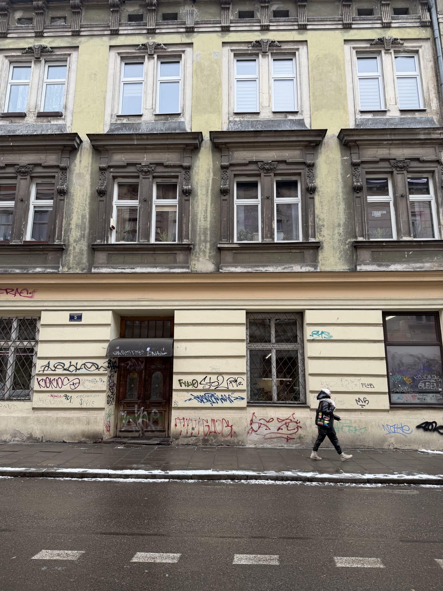 buliding with graffiti and woman walking in Kazimierz neighborhood of krakow