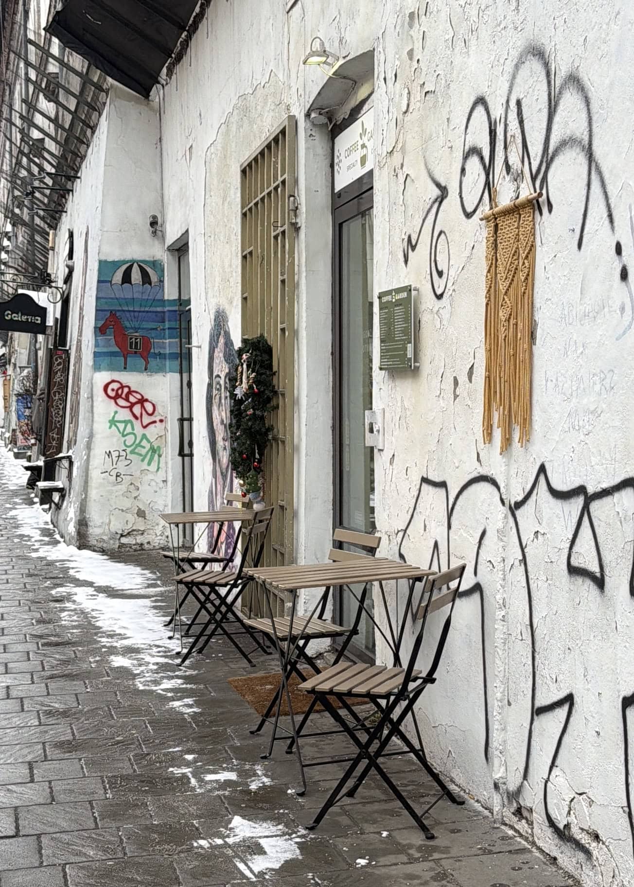 table and chairs on sidewalk with graffiti on walls behind