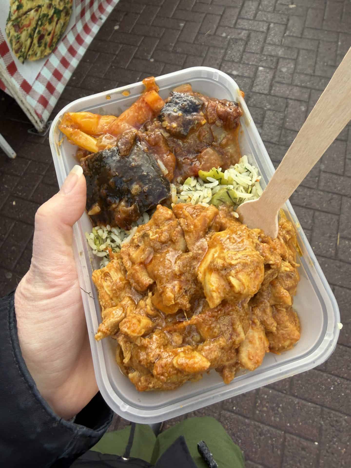 container of iraqi street food with eggplant stew, rice and chicken