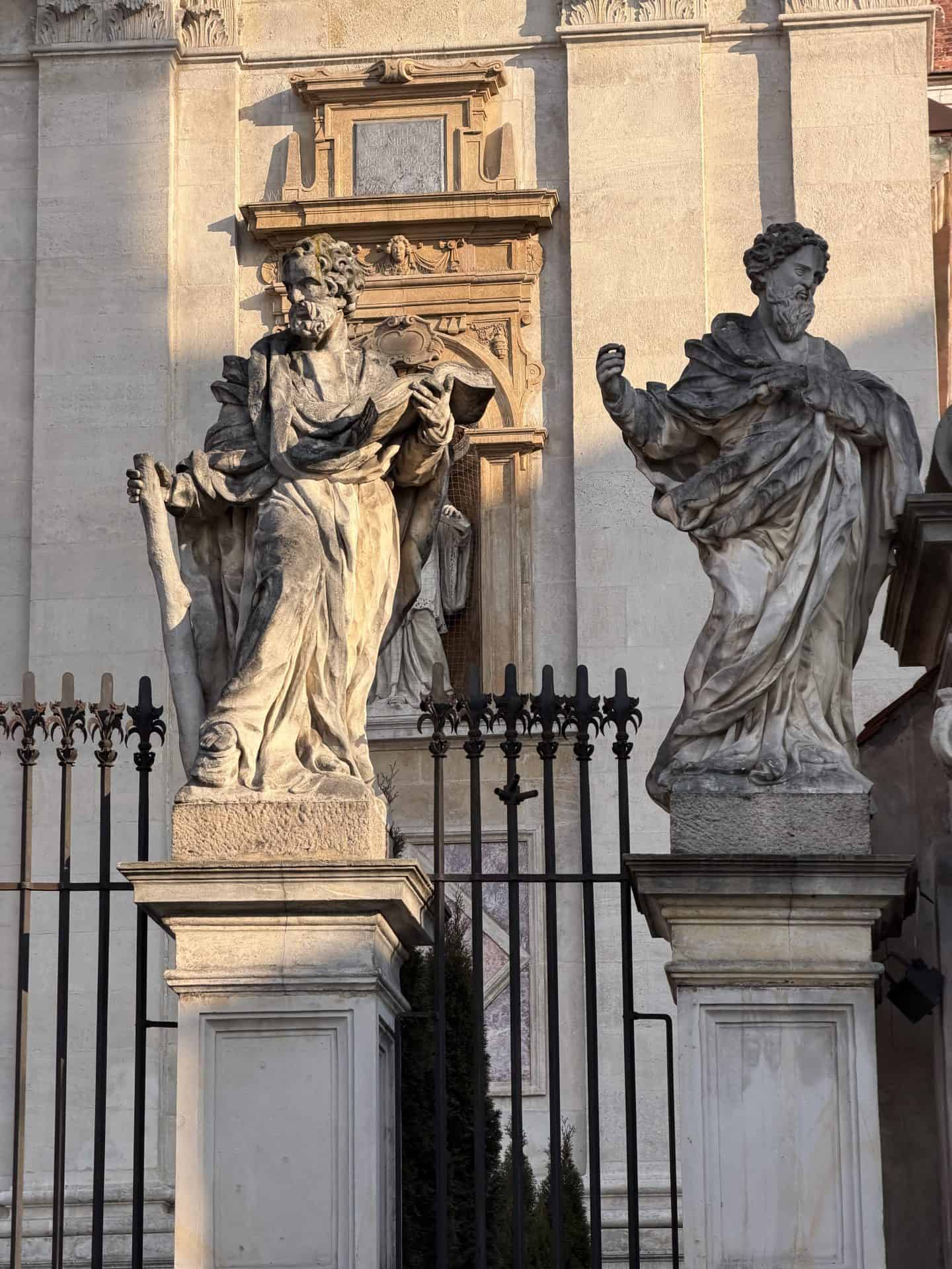 two statues on pedestals outside church in krakow
