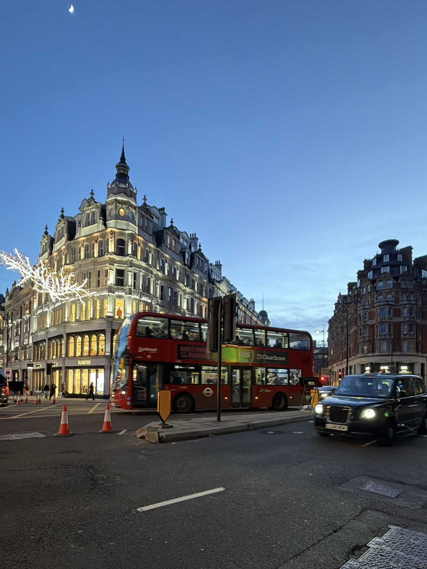 taxi and double decker bus driving on street in Knightsbridge london at dusk