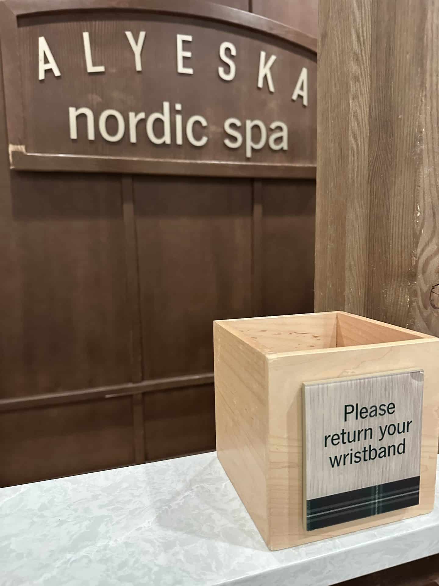 a wooden wristband return box on counter at nordic spa