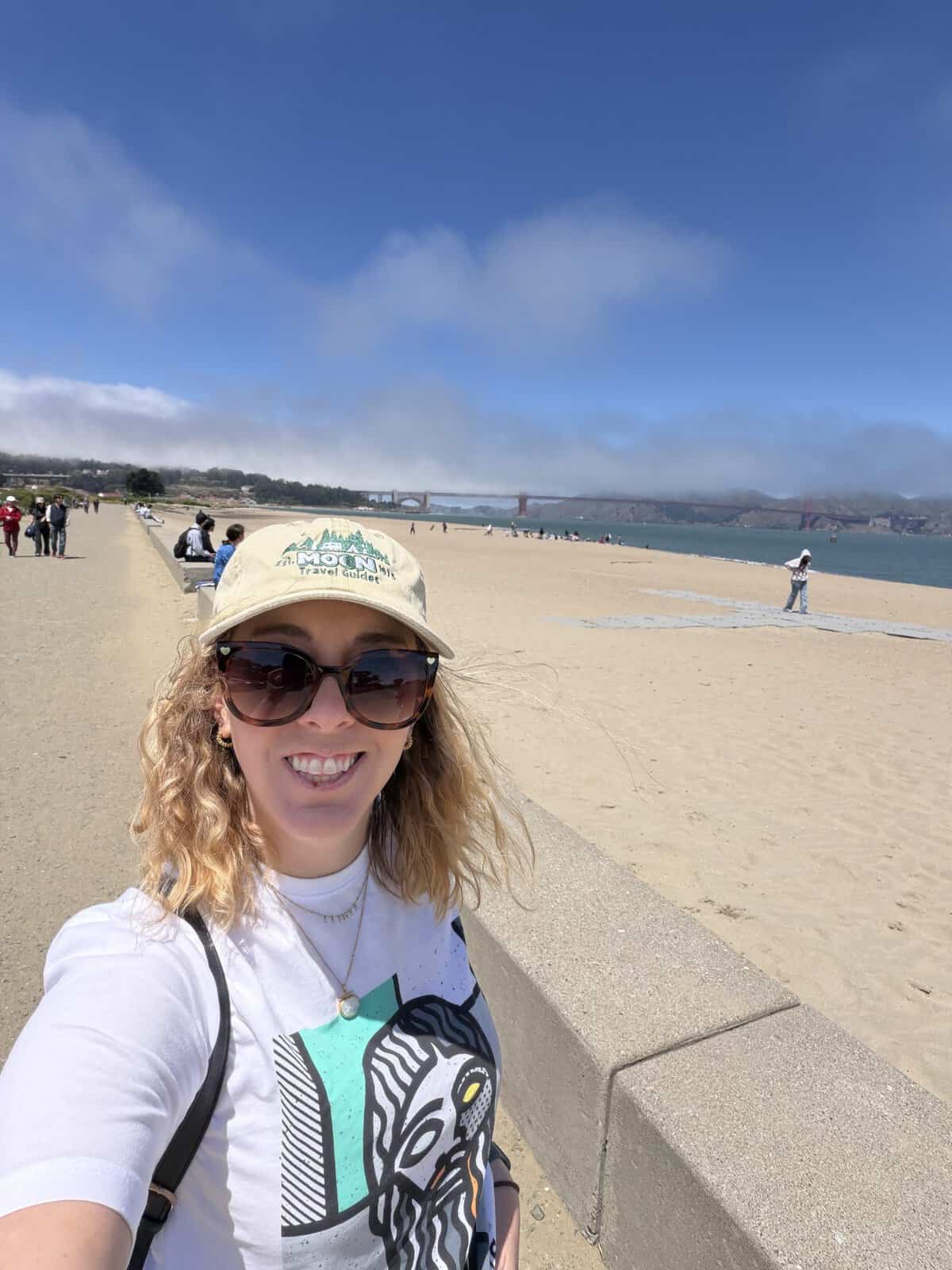 carli standing a beach with golden gate bridge in background cloaked in fog during two days in san francisco