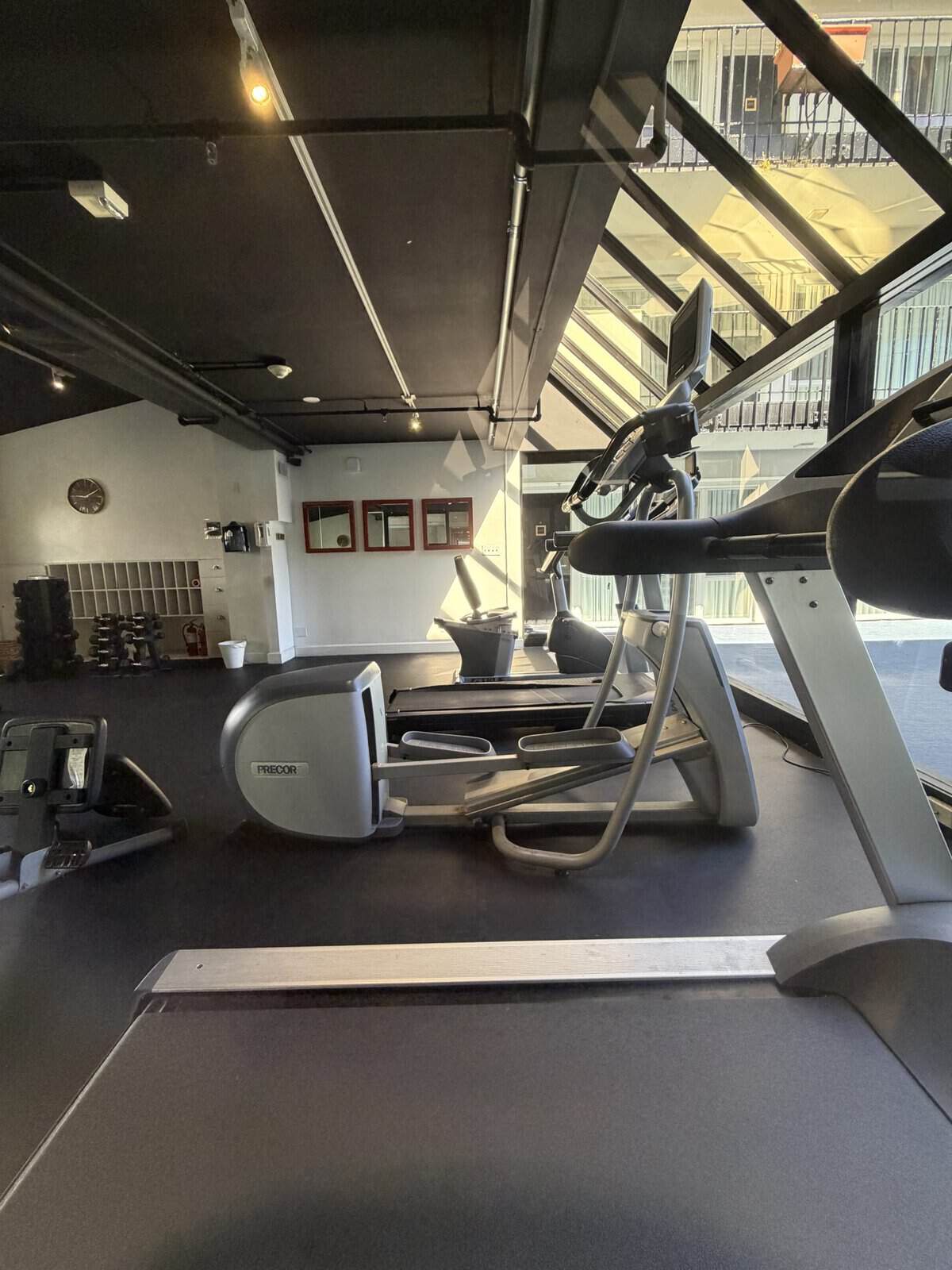 soma_house_gym - Adventures with Carli Cardio area of a gym with a treadmill in the foreground and a black ceiling, weight rack and mirrors in the background.