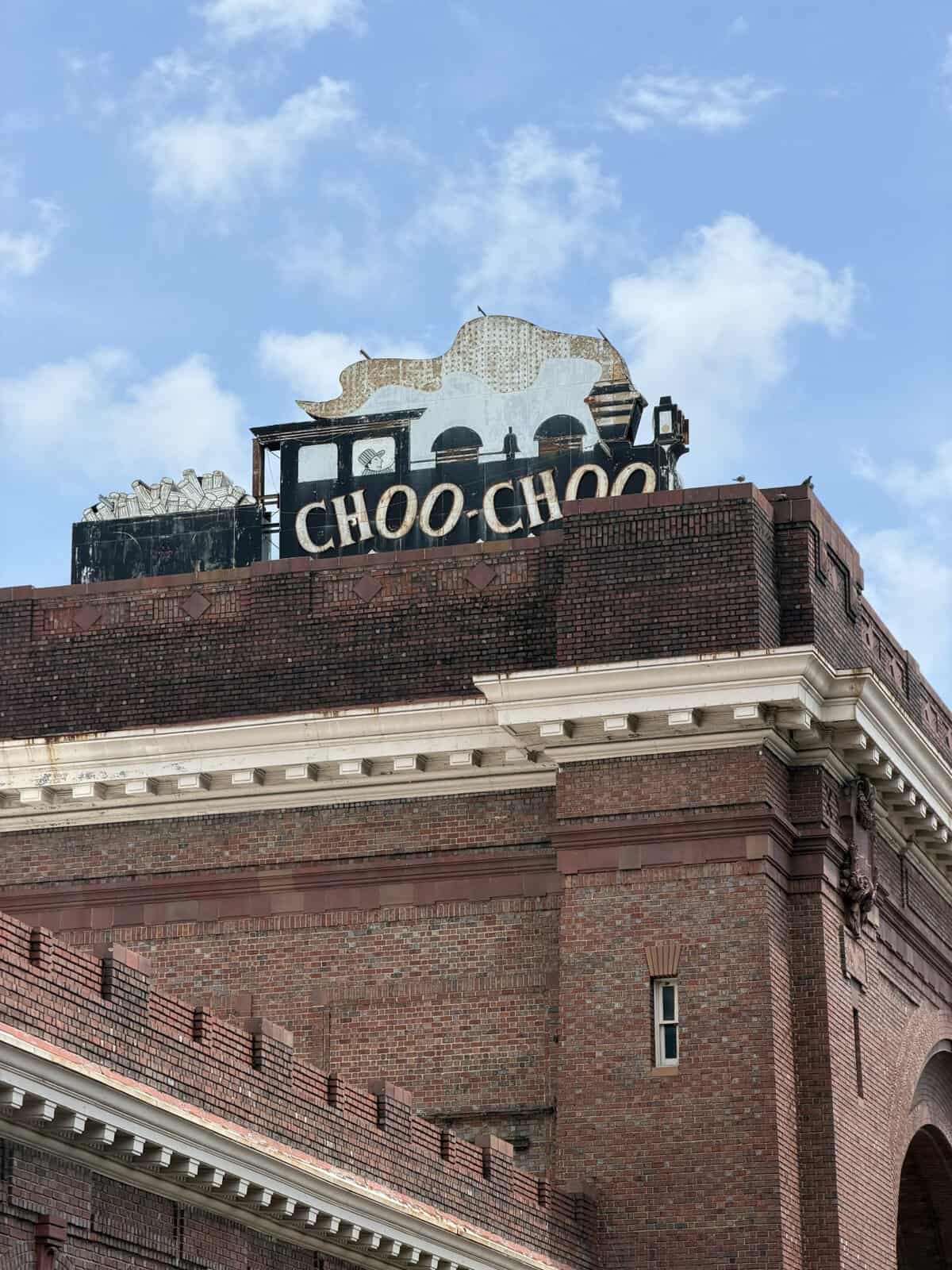 Weathered rooftop sign on a brick building reading CHOO CHOO with a train silhouette.