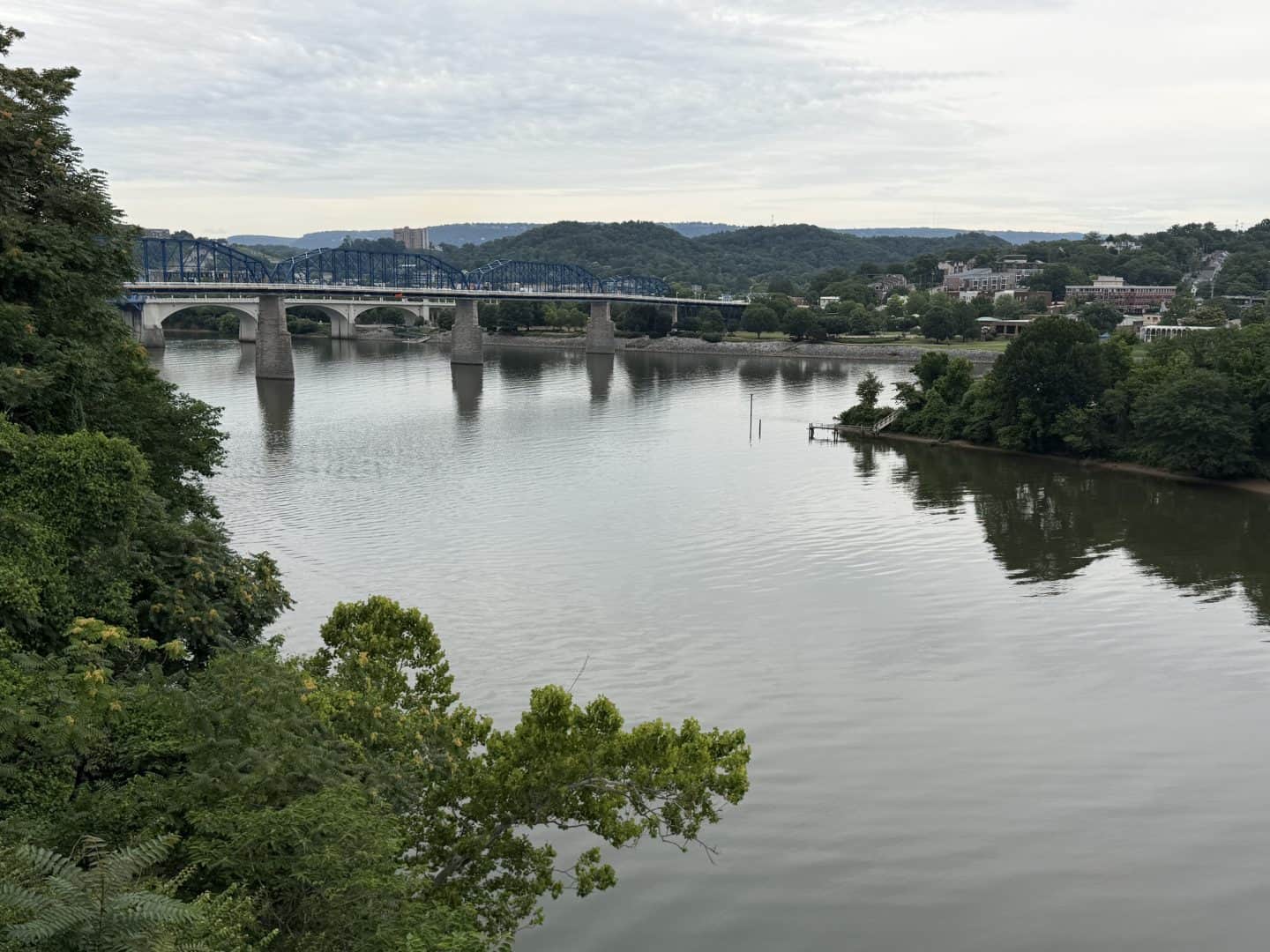 bridge over Tennessee River with mountains in distance and green trees on either side of the riverbank