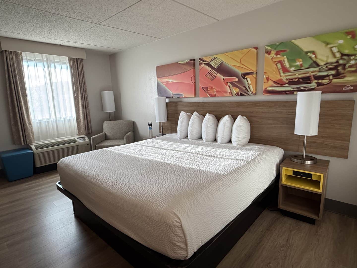 Hotel Bo Chattanooga room with a large bed, white bedding and pillows, wooden headboard, and three colorful canvases above it.