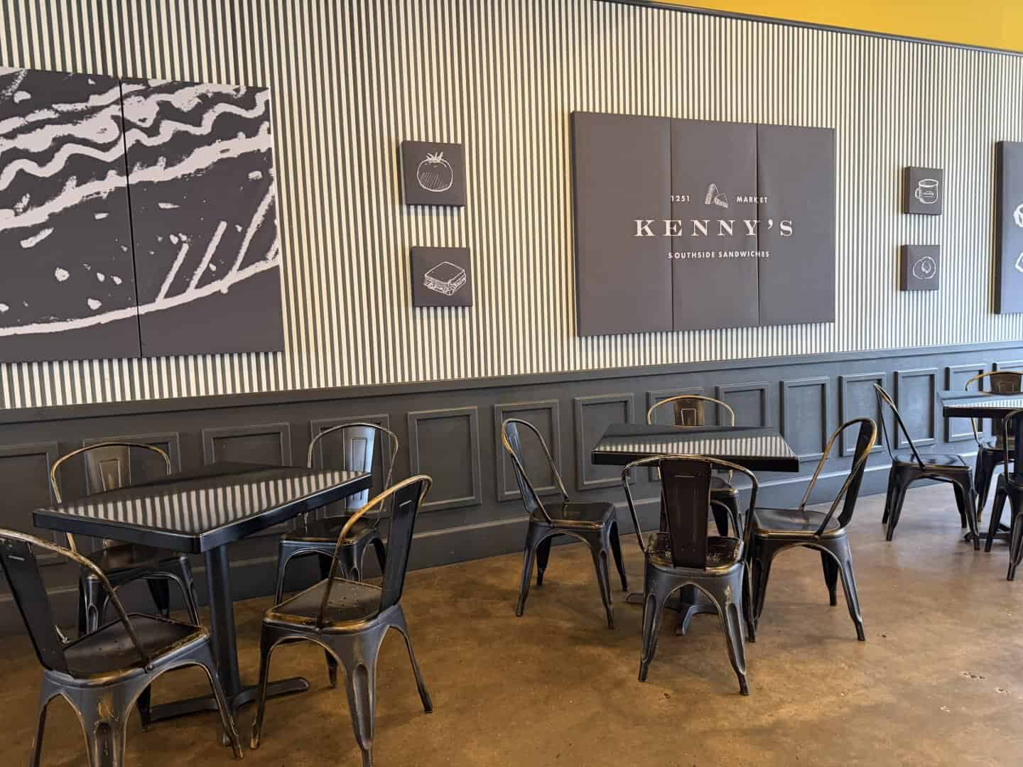 interior of kenny's sandwiches in chattanooga.  beige wallcovering, dark gray wainscott, gray metal chairs and tables, and warm wood floors. 