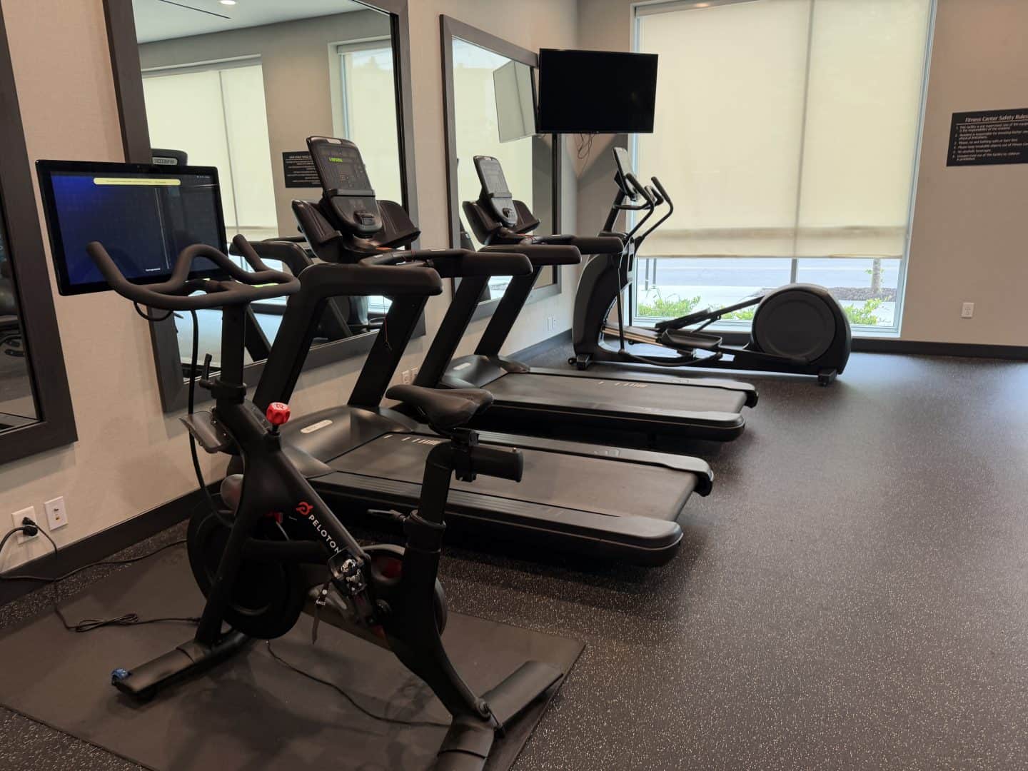 la_quinta_chattanooga_downtown_fitness_center - Adventures with Carli Row of cardio machines (treadmills and a stationary bike) in a fitness center, mirrors along the wall and large windows in the background