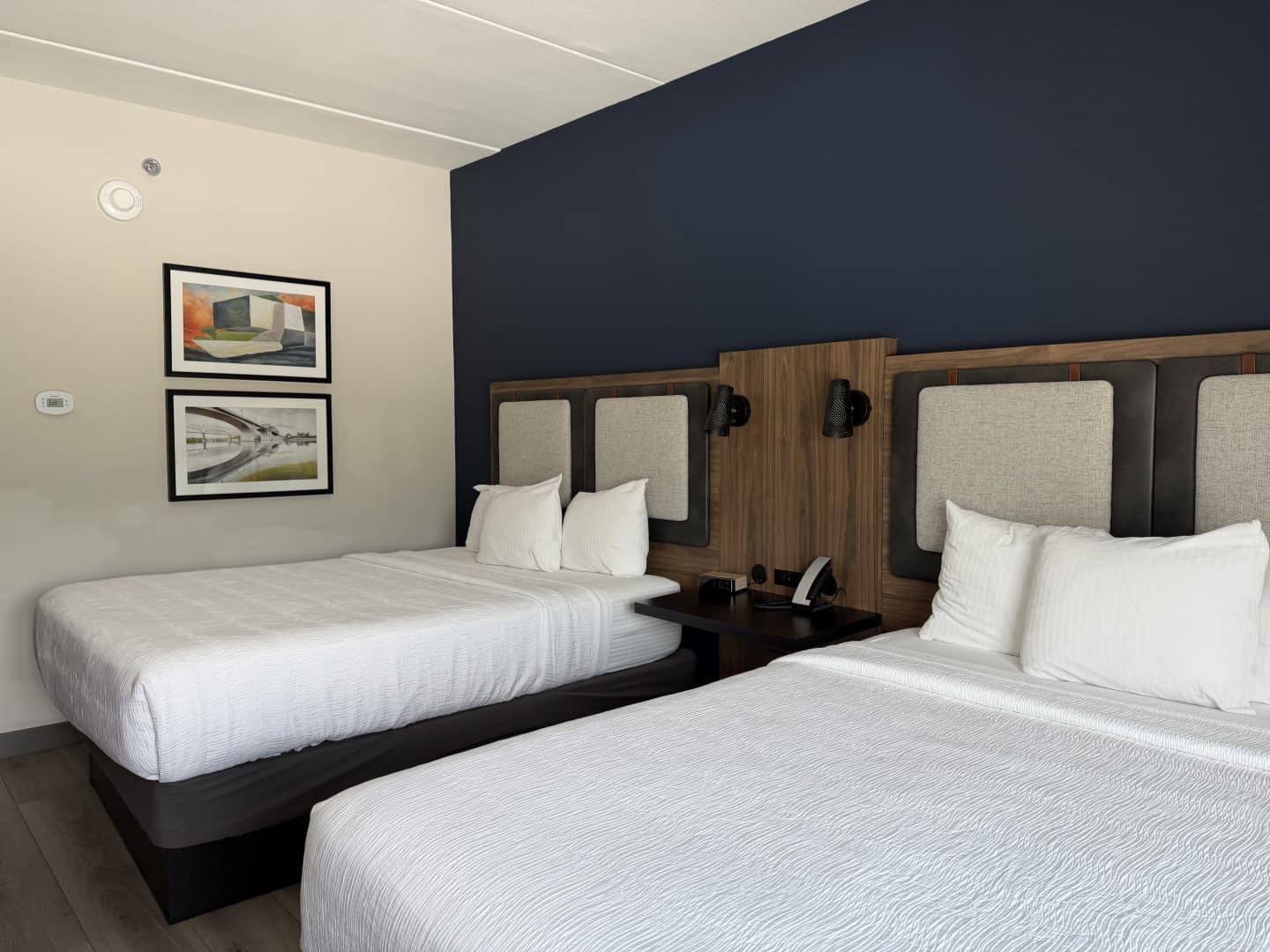 la_quinta_chattanooga_downtown_queen_room - Adventures with Carli La Quinta Chattanooga Downtown Hotel room with three single beds, white linens, and a dark blue accent wall behind the headboards.