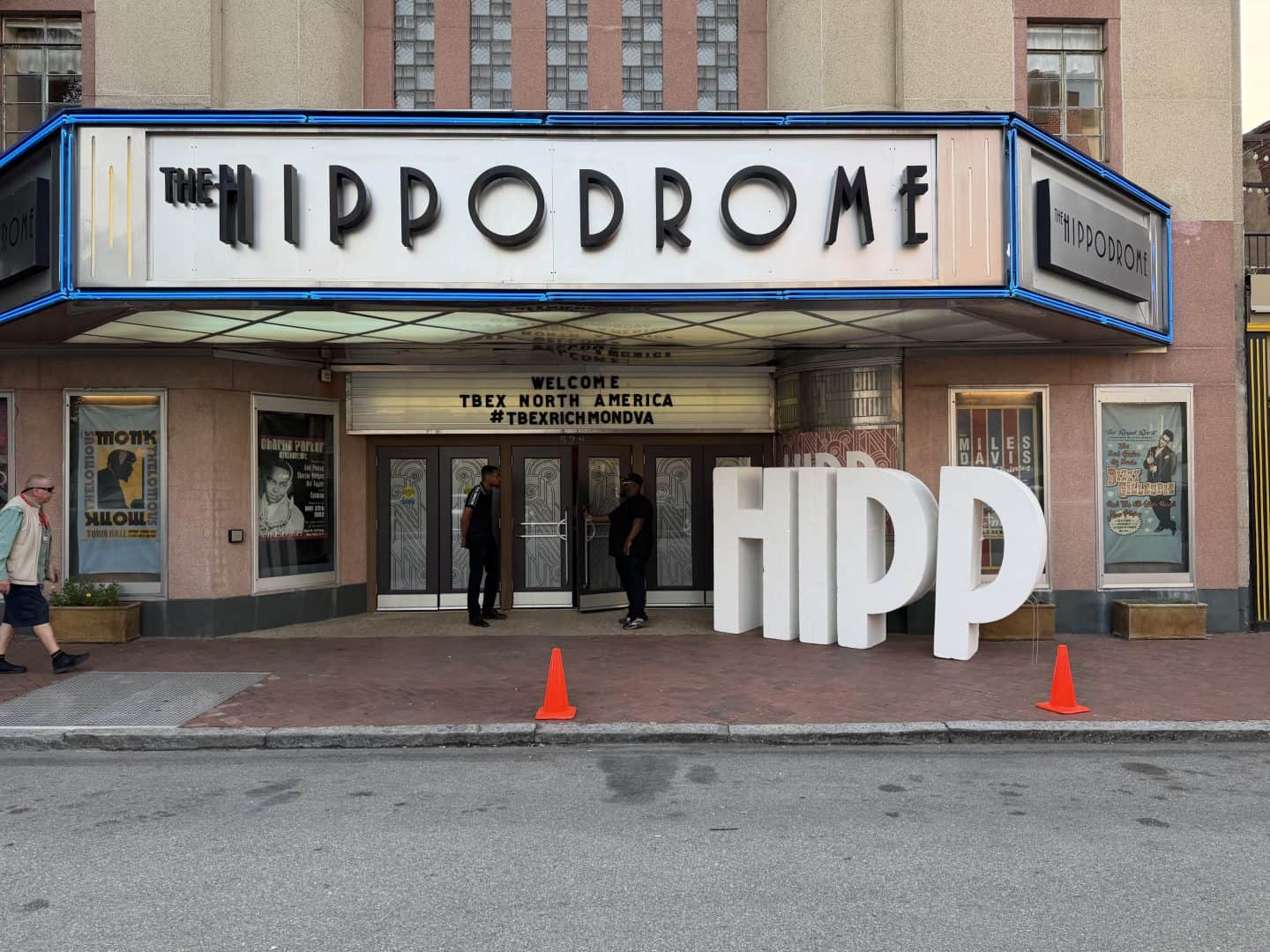 The Hippodrome theater marquee with blue neon trim and glass doors, people entering the lobby area.