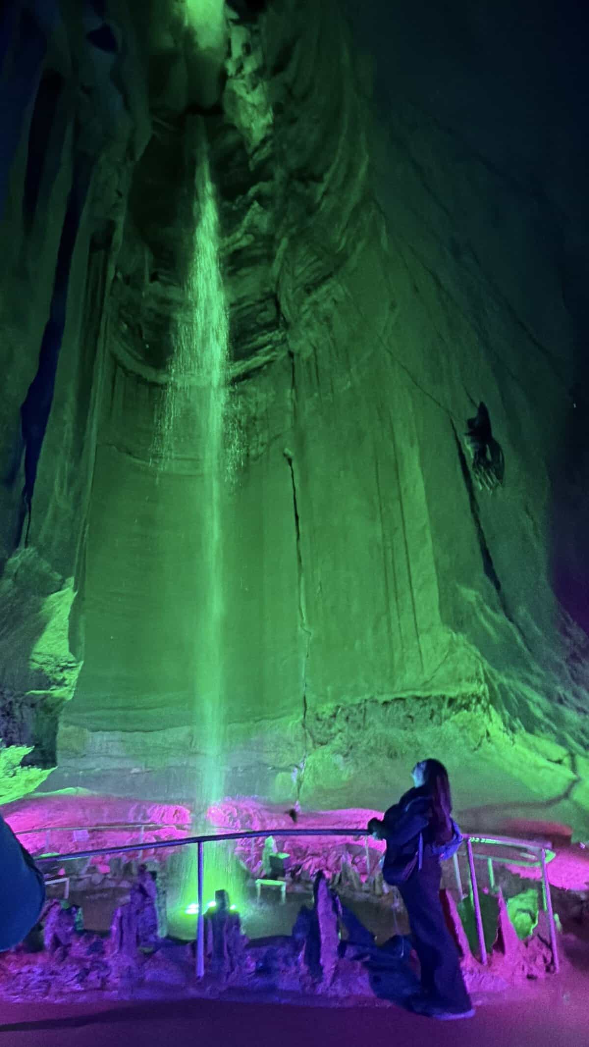 green-lit cave, with waterfall in background