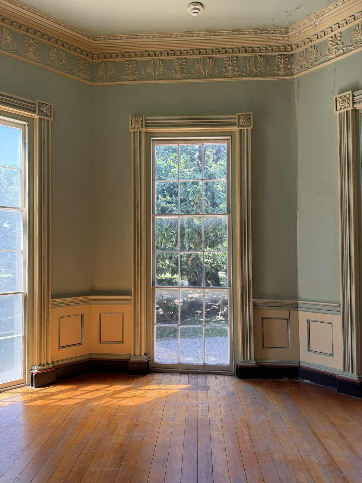 interior of violet bank museum.  warm wood floors with light green walls and ornate trim around windows and at ceiling